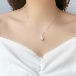 Close-up of a white pearl necklace with a diamond accent on a woman's collarbone