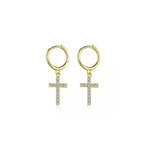 Détail de boucles d'oreilles croix dorées serties de zircons sur un fond blanc