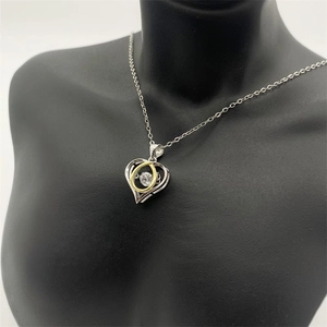 Macro detail of S925 sterling silver heart pendant with dancing stone and gold accents