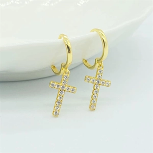 Détail macro de créoles croix dorées serties de zircons cubiques brillants pour femme
