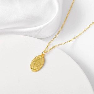 Macro shot of gold Virgin Mary Miraculous Medal pendant on elegant white silk fabric