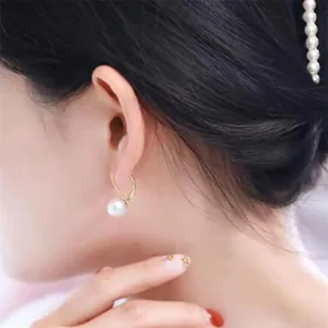 Close-up of S925 silver pearl drop earrings with gold hooks worn by a model in detail