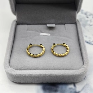 Gros plan de boucles d'oreilles créoles torsadées dorées avec zircons dans un coffret