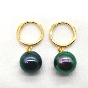 Gros plan du poinçon S925 sur boucles d'oreilles dorées avec perles vert paon