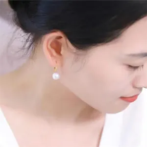 Close-up of minimalist S925 silver pearl hoop earring worn by a model on a gold ring