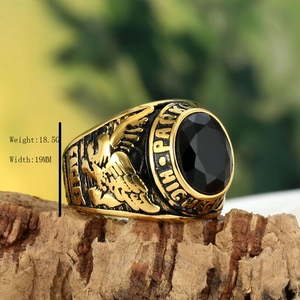 Detail of vintage gold eagle ring with black gemstone on rustic wood background