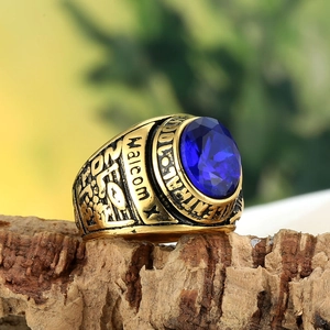 Macro detail of men's gold eagle ring with blue gemstone on textured wood base