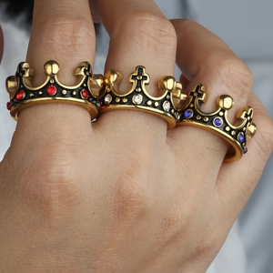 Gros plan de bagues couronne vintage serties de cristaux rouges, bleus et blancs au doigt