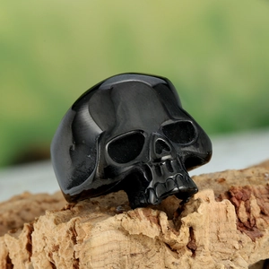 Macro shot of polished black skull ring details on natural bark background