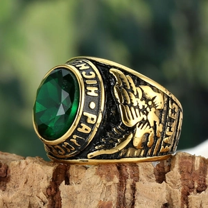 Close-up of vintage gold eagle ring with large green gemstone on wood bark
