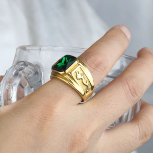 Macro shot of men's gold ring with emerald-cut green gemstone and leopard relief detail