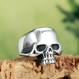 Macro shot of polished silver skull ring made of stainless steel on wooden surface