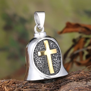 Close-up of vintage steel guardian bell pendant with gold cross on rustic wood