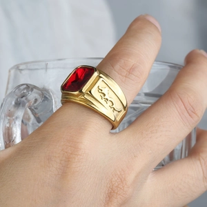 Detailed close-up of a men's titanium steel gold ring featuring a large red gemstone