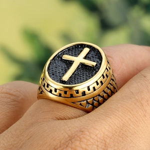 Gros plan sur une bague chevalière homme en acier doré avec emblème croix noire