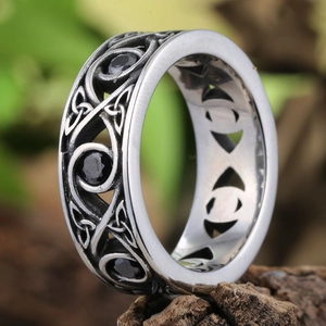 Vintage silver Celtic knot ring with black gemstones over natural wood background