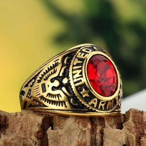 Golden United States Army military ring with red oval gemstone on rustic wood background