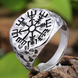 Macro detail of vintage Viking compass ring with hammered texture on a wooden base