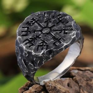 Macro detail of vintage Viking Vegvisir compass ring with rugged rock texture surface