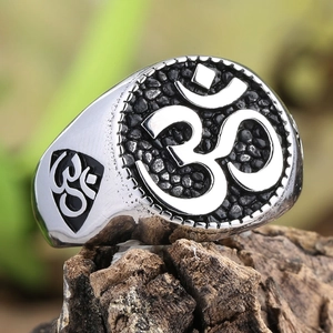 Macro detail of men's stainless steel Om ring with vintage black honeycomb texture on wood