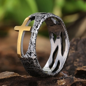 Makroaufnahme eines 304 Edelstahlrings mit rustikaler Textur und goldenem Kreuz