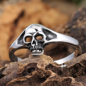 Gothic double skull heart ring in silver metal on a vintage wood texture background