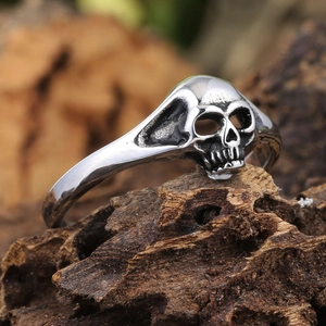 Gothic double skull heart ring in vintage steel finish resting on rustic wood bark