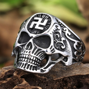 Macro detail of silver skull ring with swastika symbol and scroll relief on wood