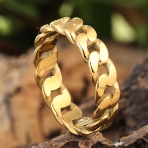 Gros plan d'une bague à maillons cubains en or poli sur une écorce de bois naturelle