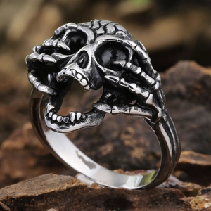 Polished stainless steel gothic ring featuring detailed skull and bone carving on a dark base