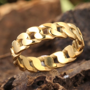 Bague chaîne gourmette dorée avec design tissé posée sur une surface en bois naturel