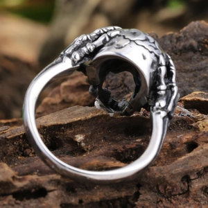 Macro view of gothic silver skull claw ring on a natural wood bark background