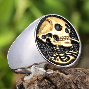 Bague en acier poli avec relief de crâne doré sur un anneau sigillaire ovale