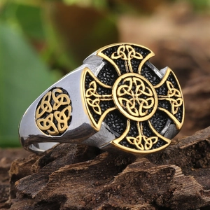 Macro detail of bicolour Viking Celtic cross ring on a natural wooden bark background