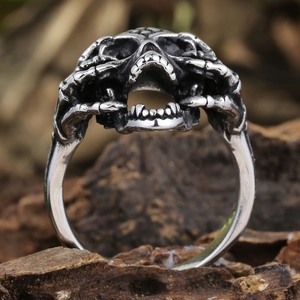 Macro shot of gothic skull ring with bone hands on textured dark bark background