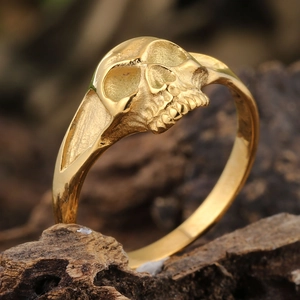 Détails macro d'une bague tête de mort gothique dorée sur un support bois