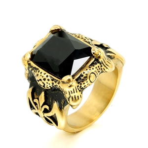 Detalle de anillo vintage dorado para hombre con piedra negra y grabado de lis