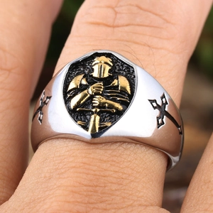 Macro detail of men's knight ring featuring a gold relief shield and black side crosses