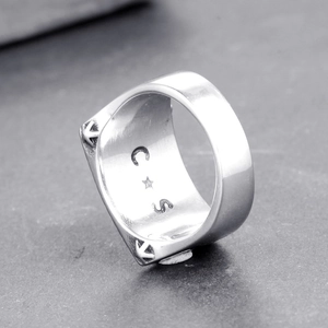 Bague punk argentée pour homme avec flèches et gravures sur une surface en pierre grise