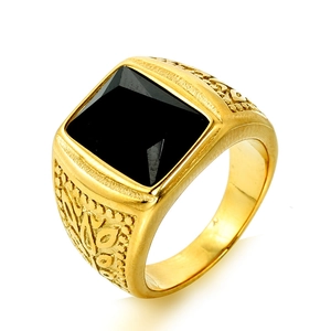 Macro shot of retro gold steel ring with square black stone and embossed floral detail