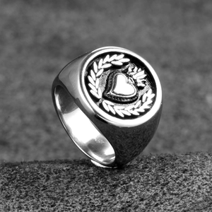 Macro detail of gothic style stainless steel signet ring with heart and olive branch relief