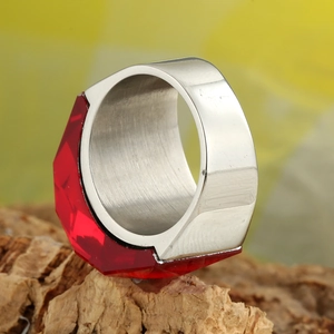 Bague large en acier inoxydable avec un grand cristal rouge facetté sur du bois
