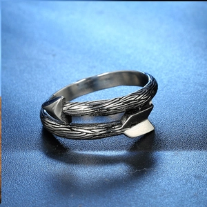 Détail macro d'une bague flèche en argent antique montrant la texture bois et plumes en métal