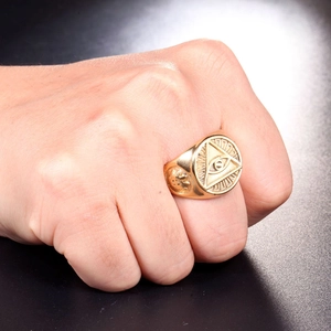 Macro detail of gold seal ring featuring the Eye of Providence and sun rays engraving