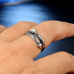 Détail macro d'une bague flèche vintage en argent oxydé avec des textures de plumes