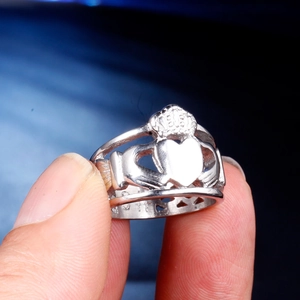 Vue macro d'une bague Claddagh en argent avec mains tenant un cœur sur le doigt