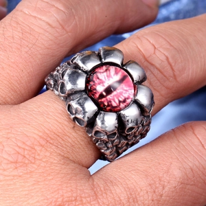 Macro detail of punk skull ring with red eye gemstone on person's finger