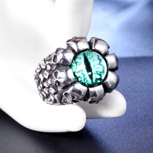 Detailed shot of retro stainless steel skull ring featuring a central green evil eye stone