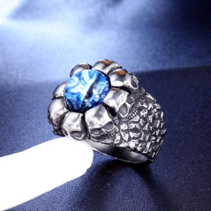 Macro detail of gothic skull ring featuring a blue eyeball gem and silver steel texture