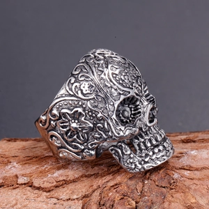 Macro detail of gothic skull ring with intricate floral carvings on rustic wood texture